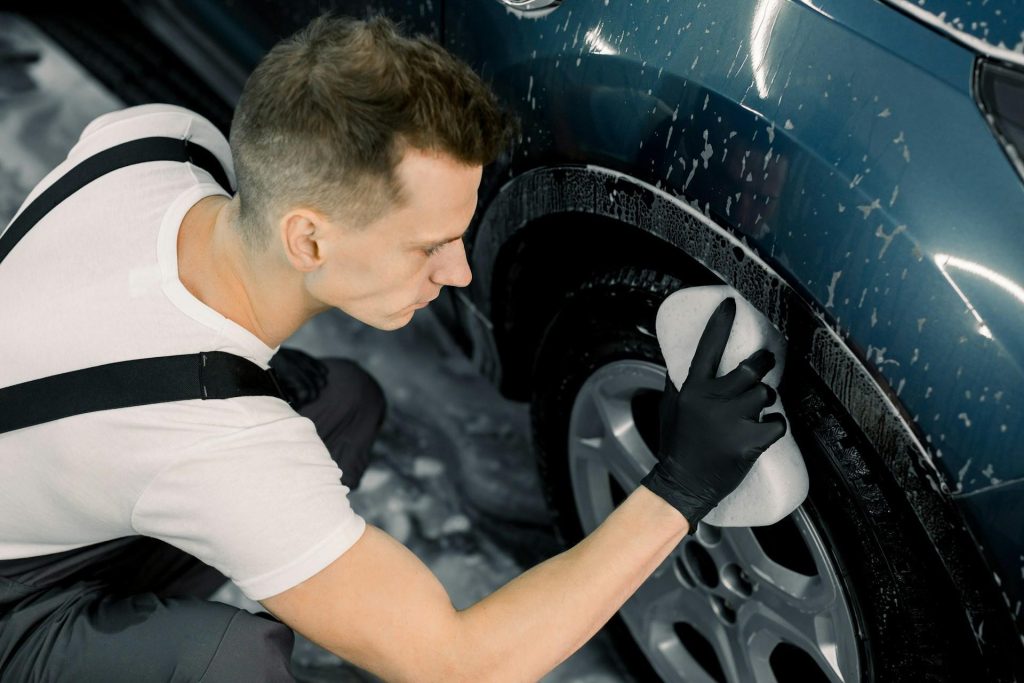 Technician cleaning and inspecting a car tire as part of regular vehicle maintenance
