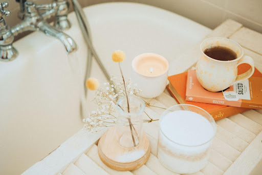 Minimal bathroom scene with candle, bath items, and coffee, reflecting a calm personal care routine